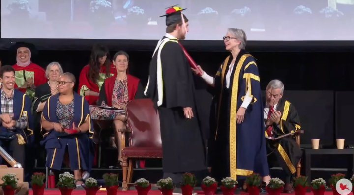 Charlie crossing the graduation stage in his propeller cap